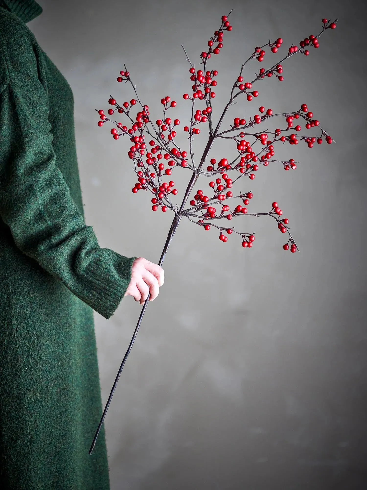 Ein künstlicher Ilex-Zweig mit leuchtend roten Beeren, ideal für stilvolle, pflegeleichte Dekorationen.