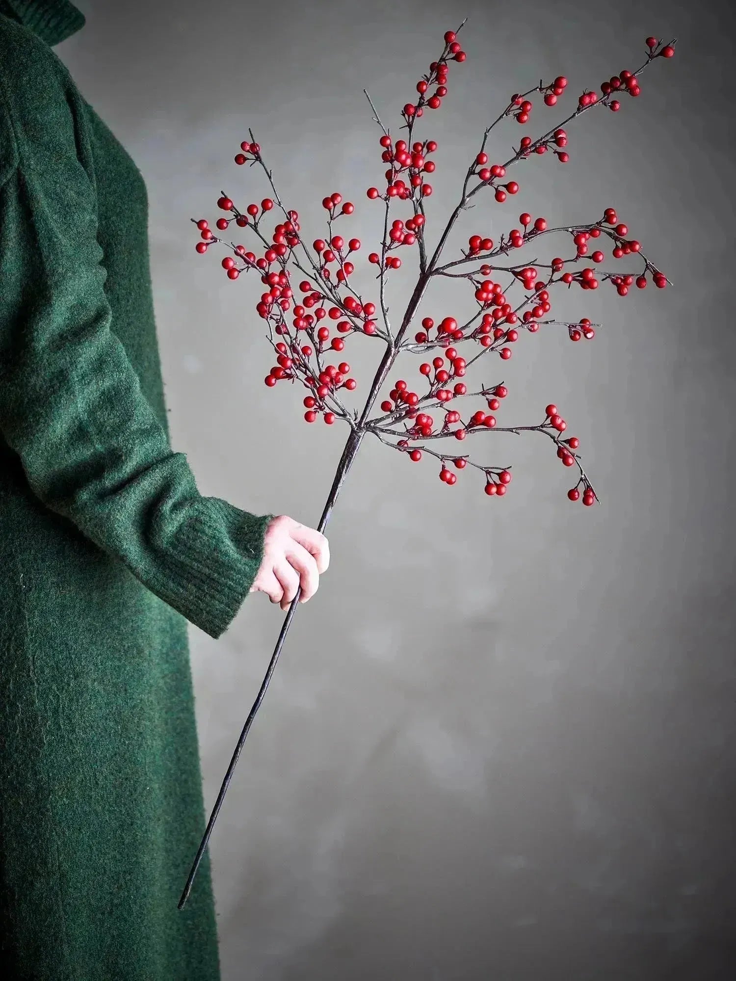 Ein künstlicher Ilex-Zweig mit leuchtend roten Beeren, ideal für stilvolle, pflegeleichte Dekorationen.