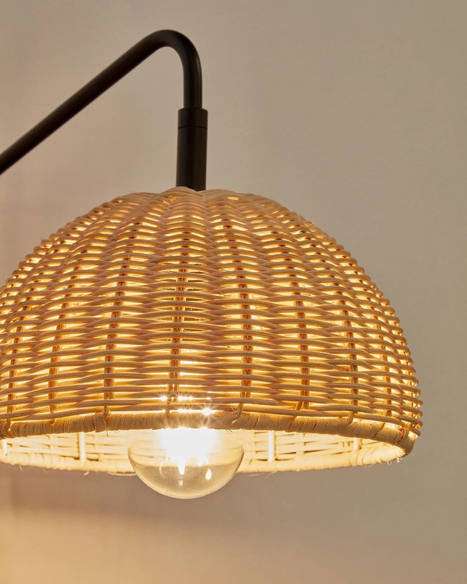 Die Damila Wandleuchte aus schwarzem Metall und Rattan verleiht jedem Raum eine elegante und gemütliche Atmosphäre.