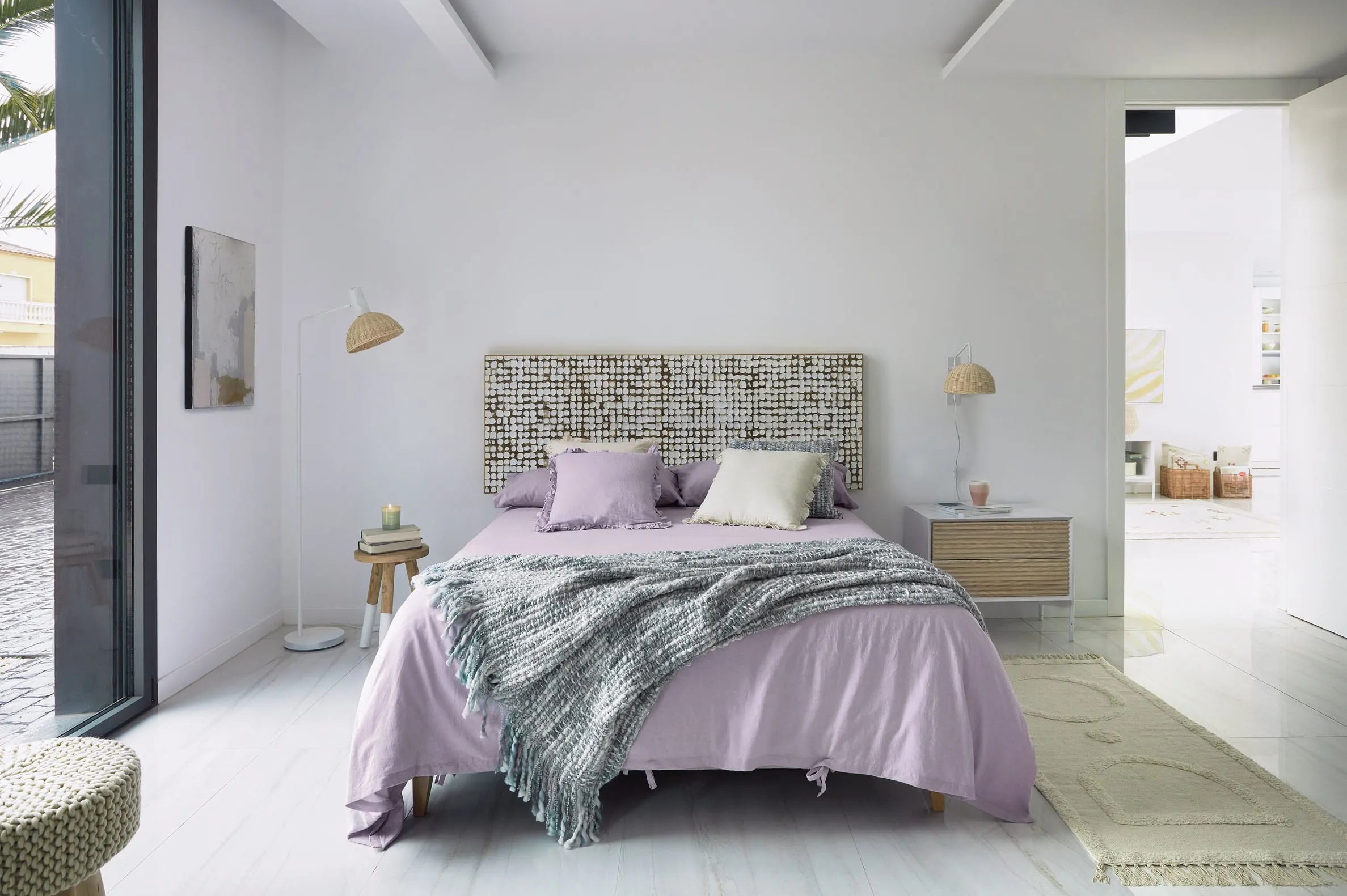 Elegante Stehlampe aus weißem Metall und handgeflochtenem Rattan, die Wärme und Stil in jeden Raum bringt.