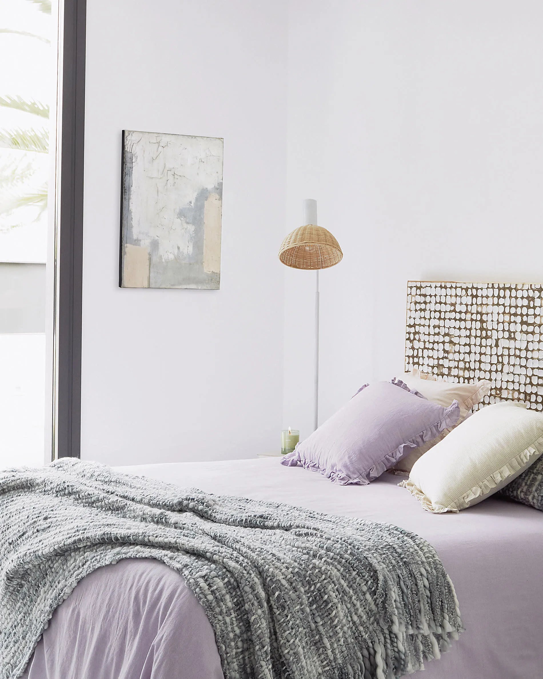 Elegante Stehlampe aus weißem Metall und handgeflochtenem Rattan, die Wärme und Stil in jeden Raum bringt.