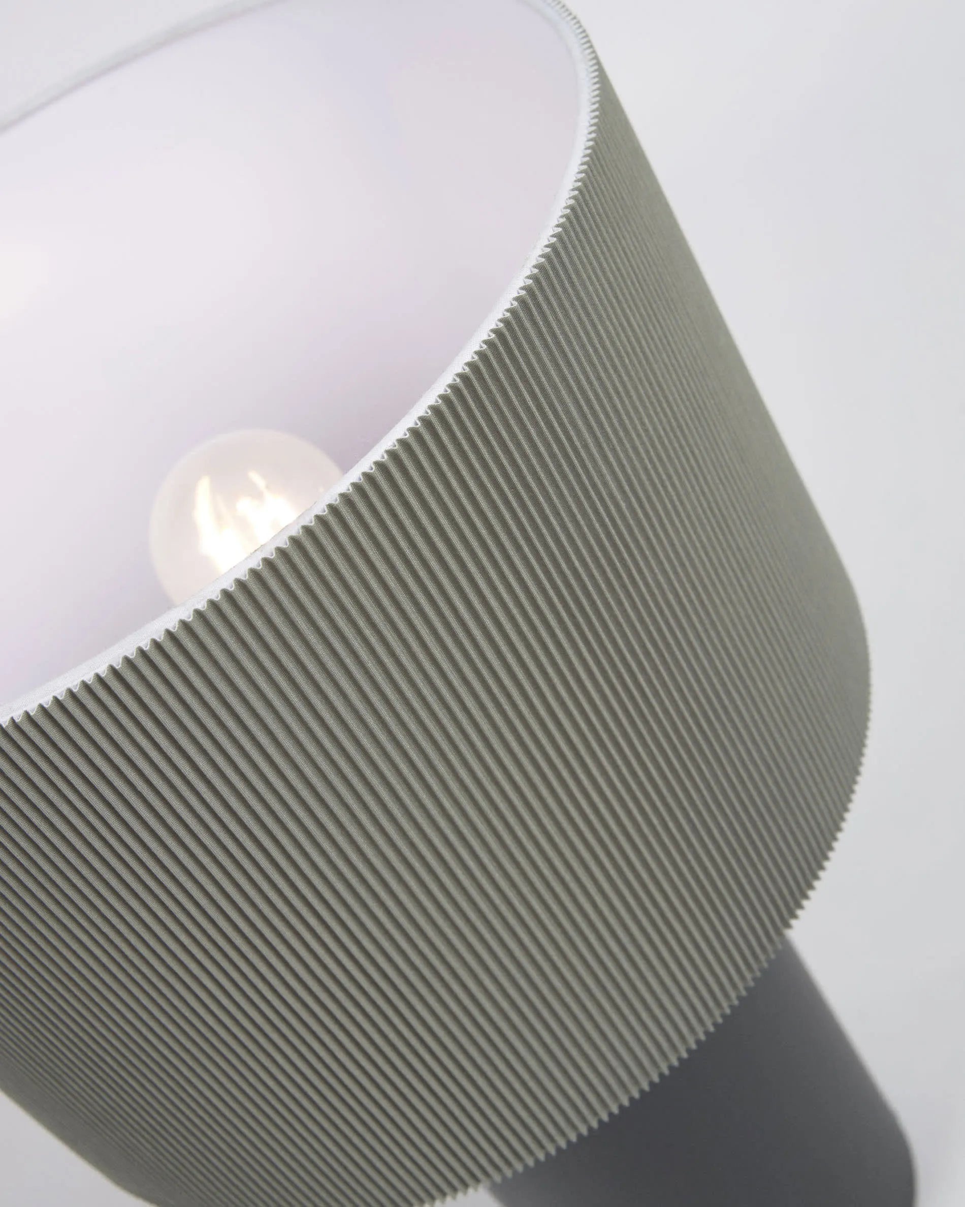 Elegante Tischlampe aus schwarzem Metall mit grauem, plissiertem Stoffschirm für stilvolle Lichtakzente.
