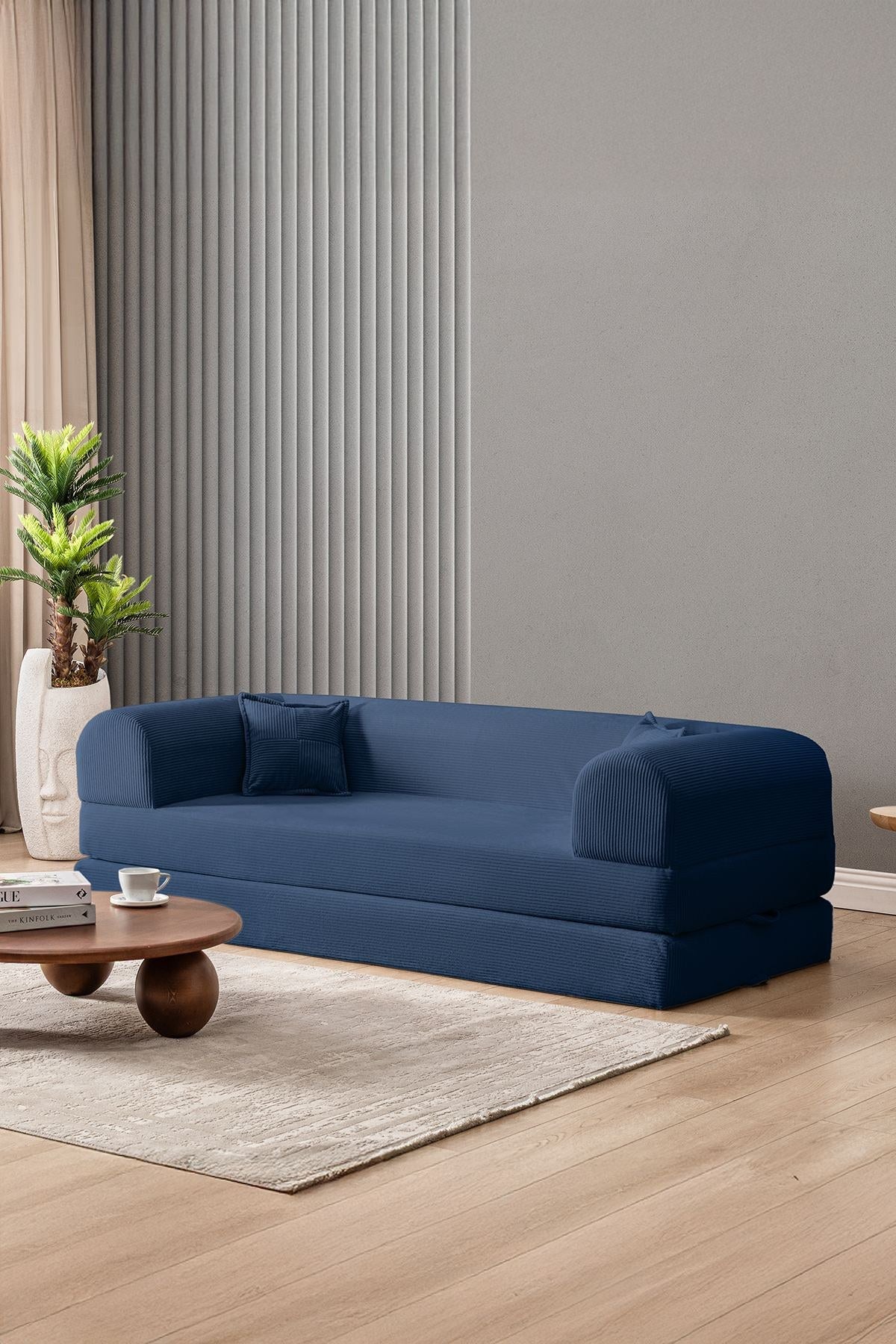 Marineblaues 3-Sitzer Schlafsofa Legom Eco von Hanah Home aus geripptem Cord-Plüschstoff mit zwei Kissen und niedrigem Rückenteil.