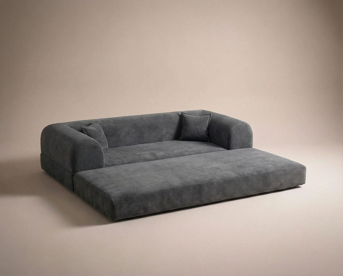 Anthrazitfarbenes 3-Sitzer Schlafsofa aus geripptem Cord-Plüschstoff mit zwei Kissen und sichtbarer rutschfester Sohle.