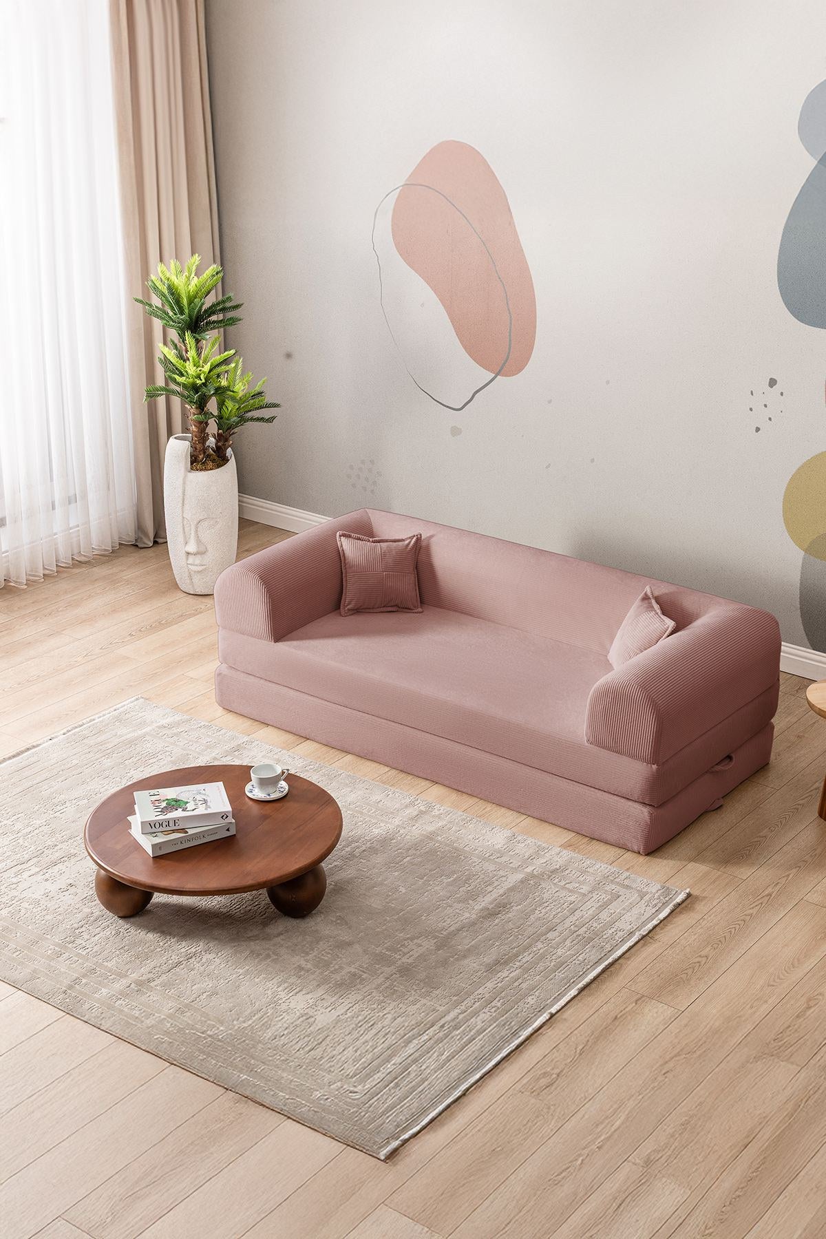 Rosafarbenes 3-Sitzer Schlafsofa aus geripptem Cord-Plüschstoff mit zwei Kissen und rutschfester Sohle, Frontalansicht auf hellem Hintergrund.