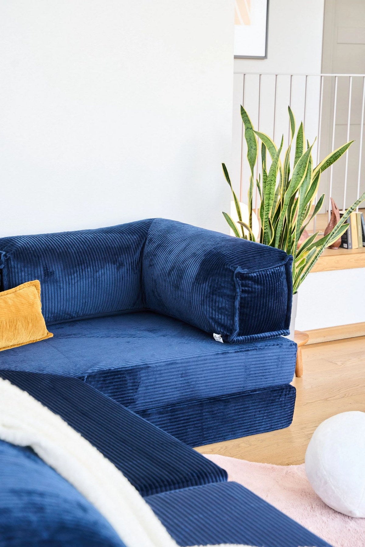 Marineblaues Eck-Schlafsofa aus Cord-Plüschstoff mit vier Kissen, Rollpack-Verpackung und abnehmbarem, waschbarem Bezug.