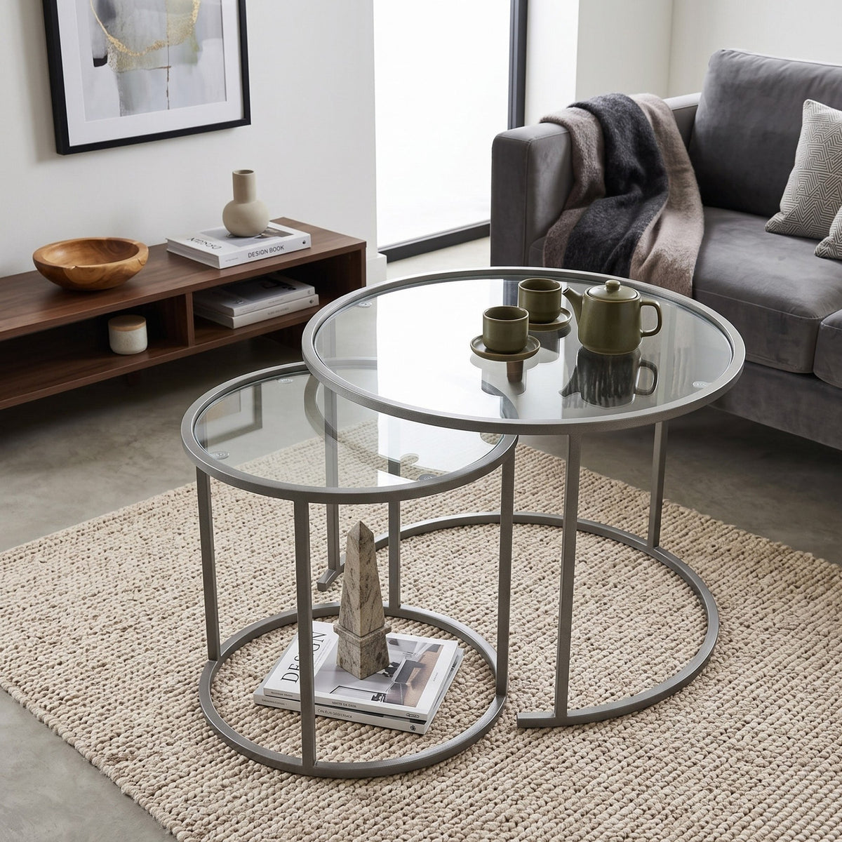 Zwei graue Couchtische aus gehärtetem Glas mit schlankem Metallgestell, unterschiedliche Grössen, nordisches Design, freistehend fotografiert.