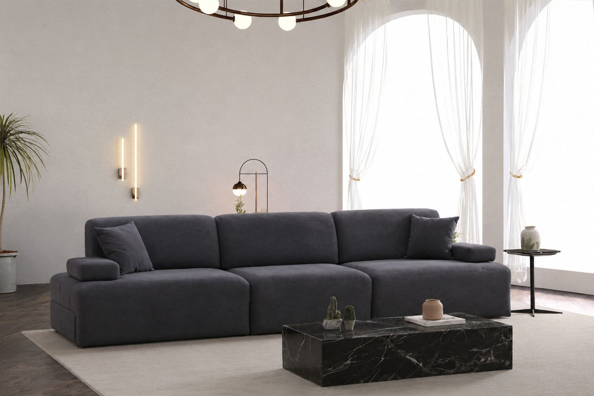 Petrolblaues 4-Sitzer Sofa Madlen mit niedrigen Kunststoffbeinen, Polyesterbezug, zwei Kissen und sichtbarem Staufach unter der Sitzfläche.
