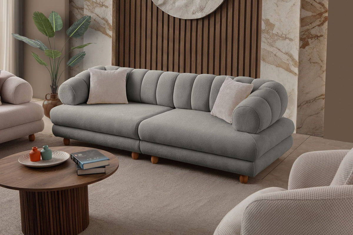 Graues 3-Sitzer Sofa Gloria von Hanah Home mit Polyesterbezug in Tuna-Struktur, Holzbeinen und zwei losen Kissen auf hellem Untergrund.