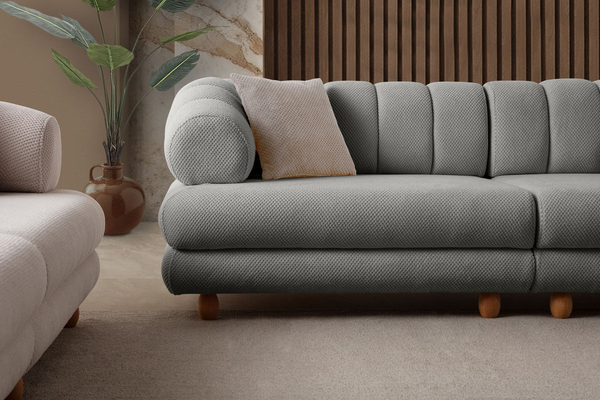 Graues 3-Sitzer Sofa Gloria von Hanah Home mit Polyesterbezug in Tuna-Struktur, Holzbeinen und zwei losen Kissen auf hellem Untergrund.