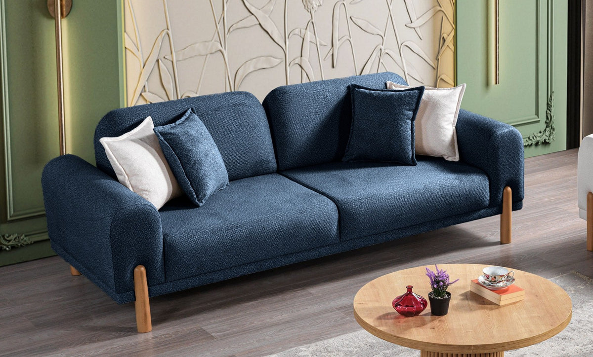 Marineblaues 3-Sitzer Schlafsofa Class Bohem mit flauschigem Bouclé-Bezug, Holzbeinen und vier Kissen, fotografiert auf hellem Hintergrund.
