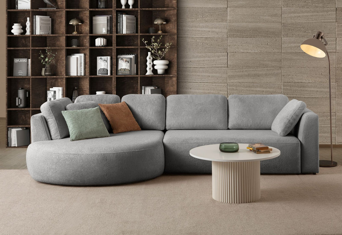 Graues Ecksofa Venezia links von Hanah Home mit Polyesterbezug, Hainbuche-Gestell, Kunststoffbeinen und neun Kissen im Wohnraum.