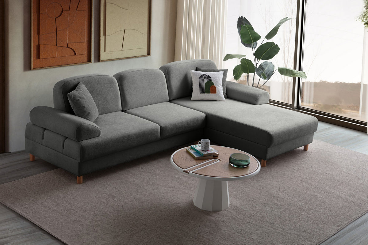 Anthrazitfarbenes Eck-Schlafsofa Aries von Hanah Home mit Coco-Boucle-Bezug, Holzbeinen und ausklappbarer Liegefläche in Wohnraumumgebung.