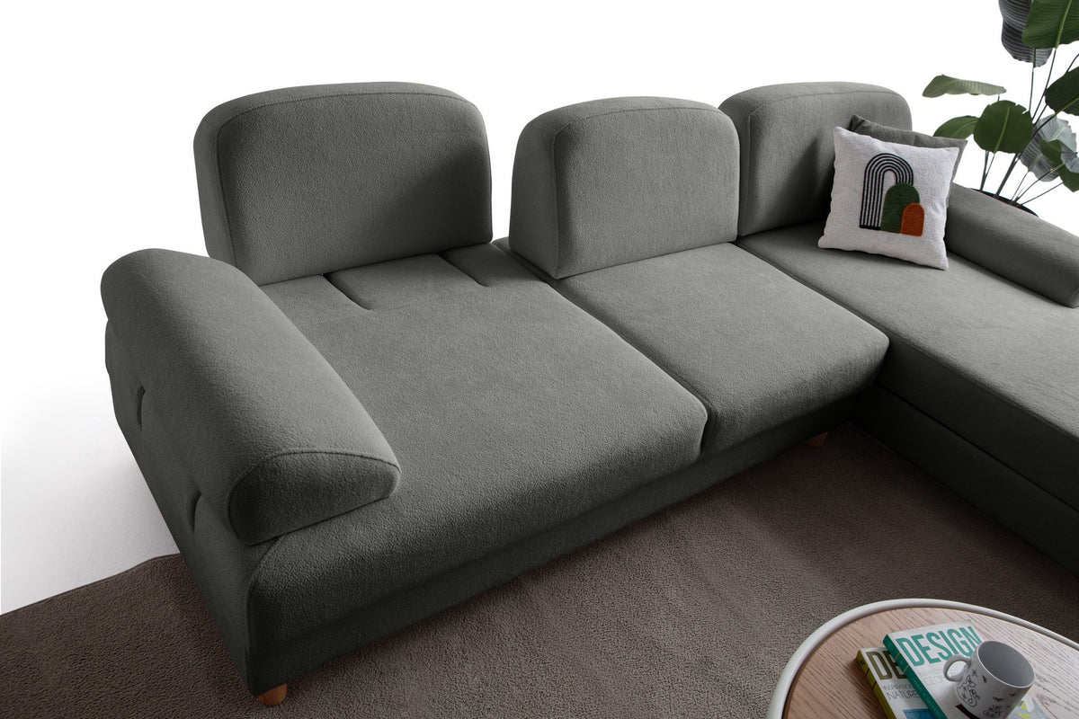 Anthrazitfarbenes Eck-Schlafsofa Aries von Hanah Home mit Coco-Boucle-Bezug, Holzbeinen und ausklappbarer Liegefläche in Wohnraumumgebung.