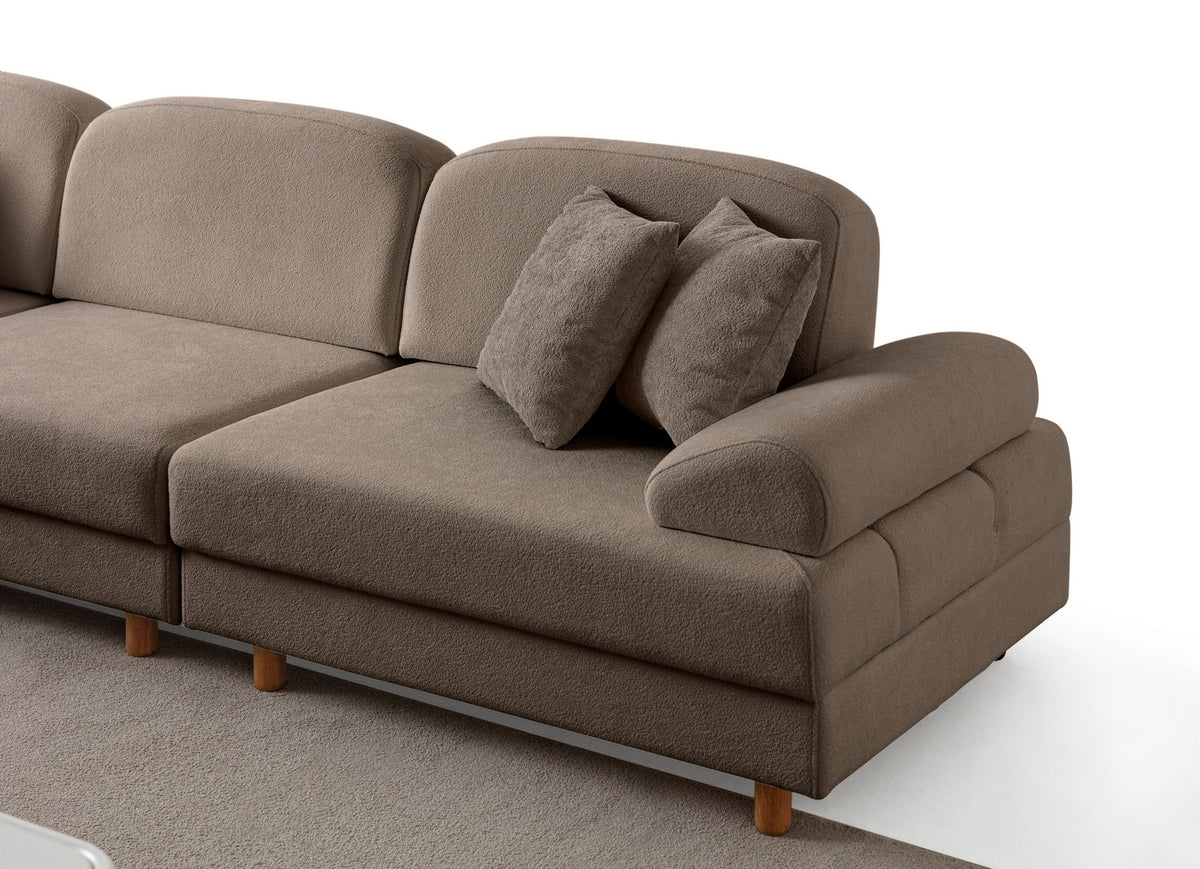 Braunes Eck-Schlafsofa Aries Modular S von Hanah Home mit Coco-Boucle-Stoff, Holzbeinen und vier Kissen in einem Wohnzimmer.