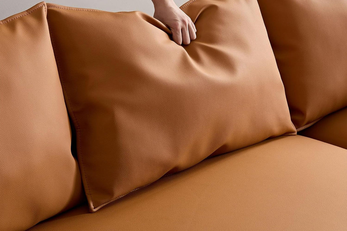 Oranges Ecksofa Venedik von Hanah Home mit glattem Kunstlederbezug, Holzgestell, Kunststoffbeinen und sieben losen Kissen im Wohnraum