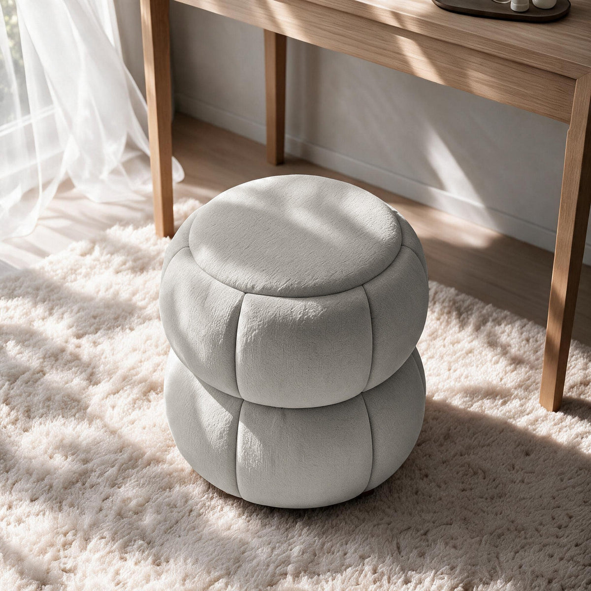 Runder Pouf in Hellgrau mit gestricktem Polyesterbezug, Holzkugelfüssen und gepolstertem Sitzbereich auf hellem Hintergrund fotografiert.