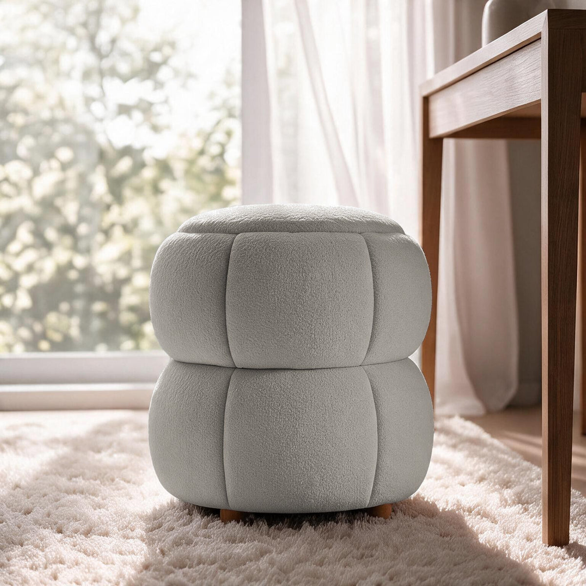 Runder Pouf in Hellgrau mit gestricktem Polyesterbezug, Holzkugelfüssen und gepolstertem Sitzbereich auf hellem Hintergrund fotografiert.