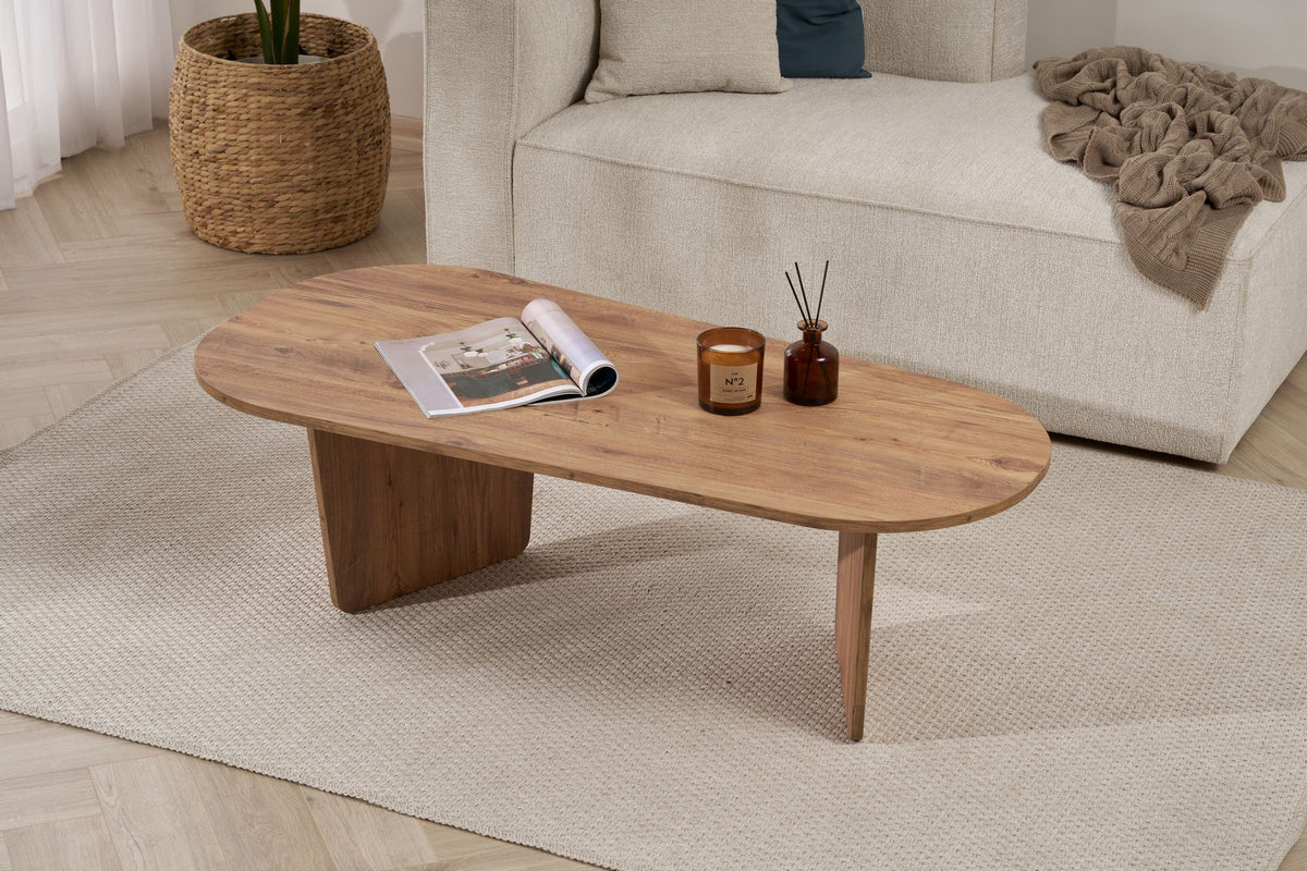 Ovaler Couchtisch in Atlantik-Kiefer Optik von Nordure aus melaminbeschichteter Spanplatte, 130 cm breit, 65 cm tief, 40 cm hoch, im Wohnraum platziert.