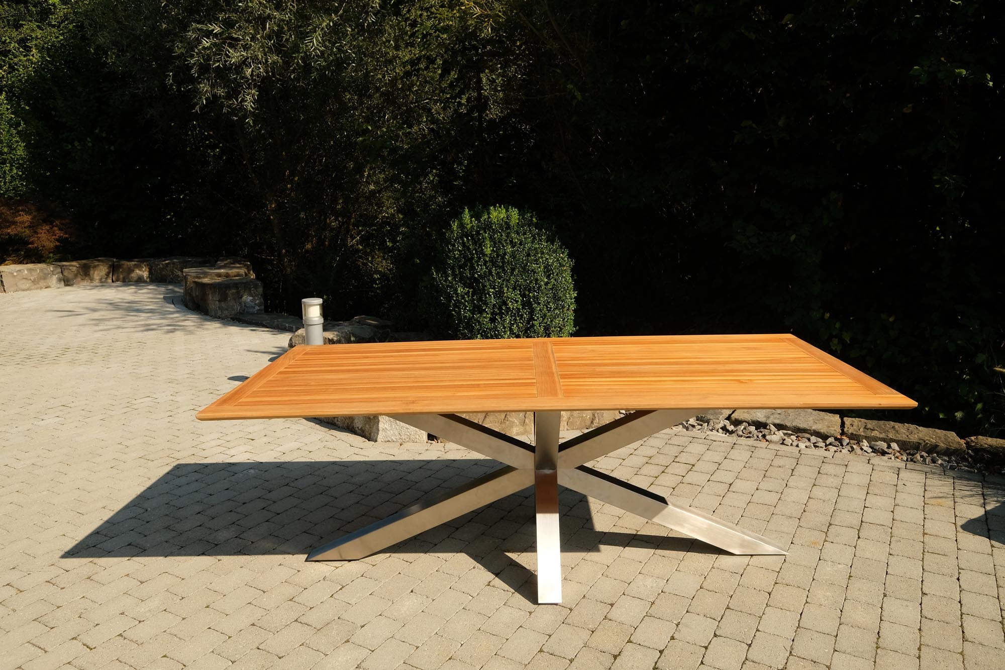 Eleganter Gartentisch Monaco mit stabilen XX-Füßen und hochwertiger Teakholzplatte, ideal für stilvolle Outdoor-Entspannung.