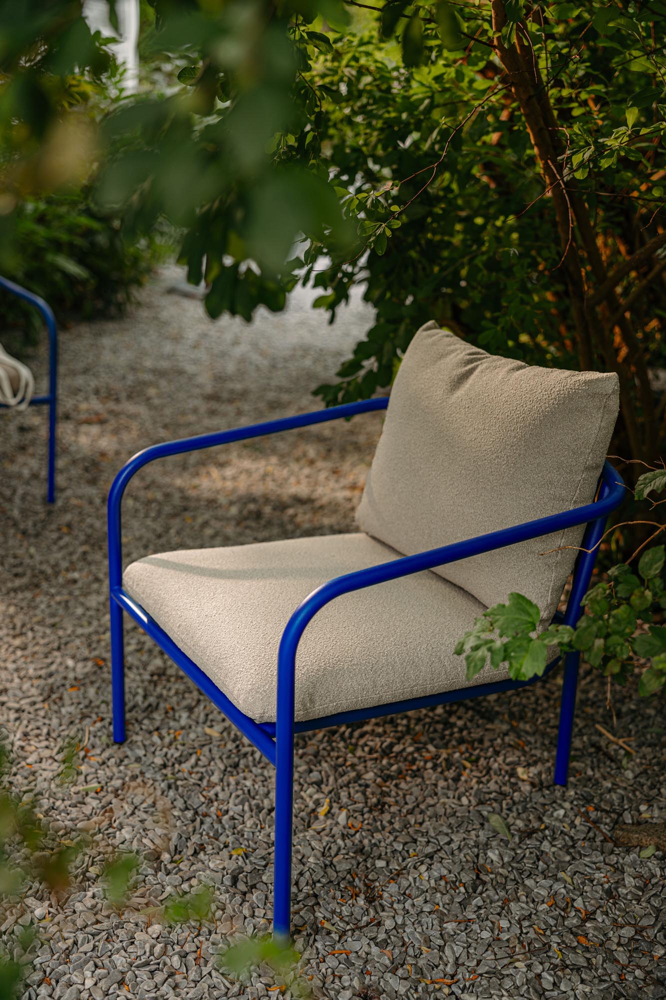 Stylischer Outdoor-Sessel Bendt in Blau-Beige mit Armlehnen, ideal für gemütliche Momente im Garten oder auf der Terrasse.