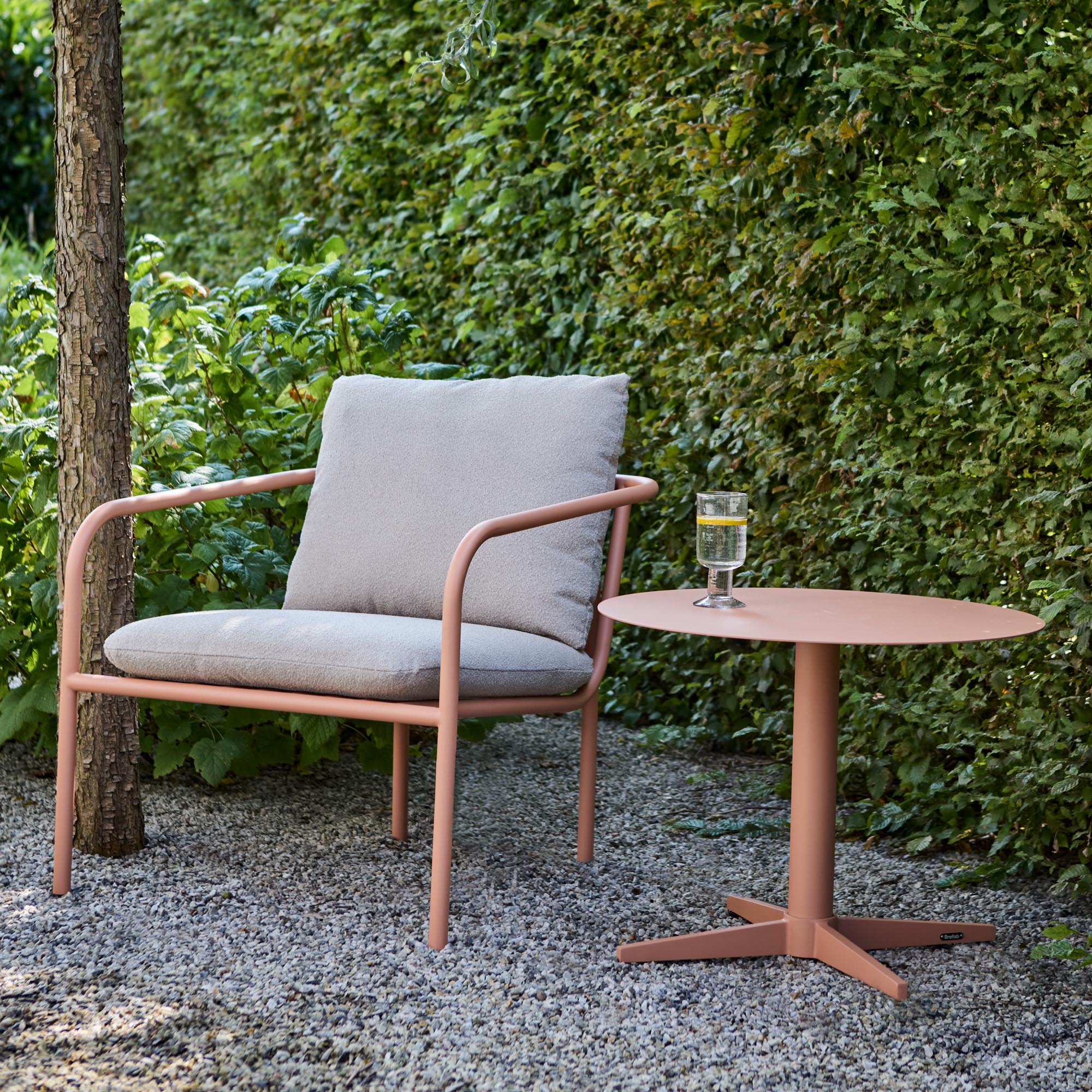 Stylischer Outdoor-Sessel Bendt mit bequemen Armlehnen in warmen Pfirsich-beigen Nuancen, ideal für gemütliche Gartenmomente.