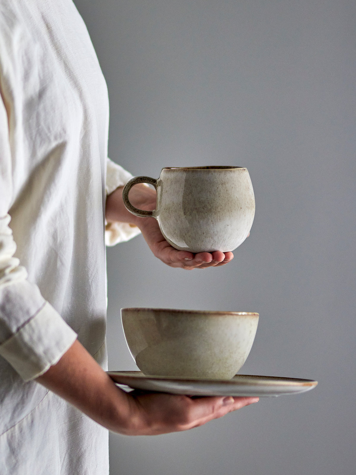 Beiger Becher aus Steingut der Serie Sandrine von Bloomingville, mit reaktiver Glasur und leicht ungleichmässiger Oberfläche, handgefertigt in Portugal.