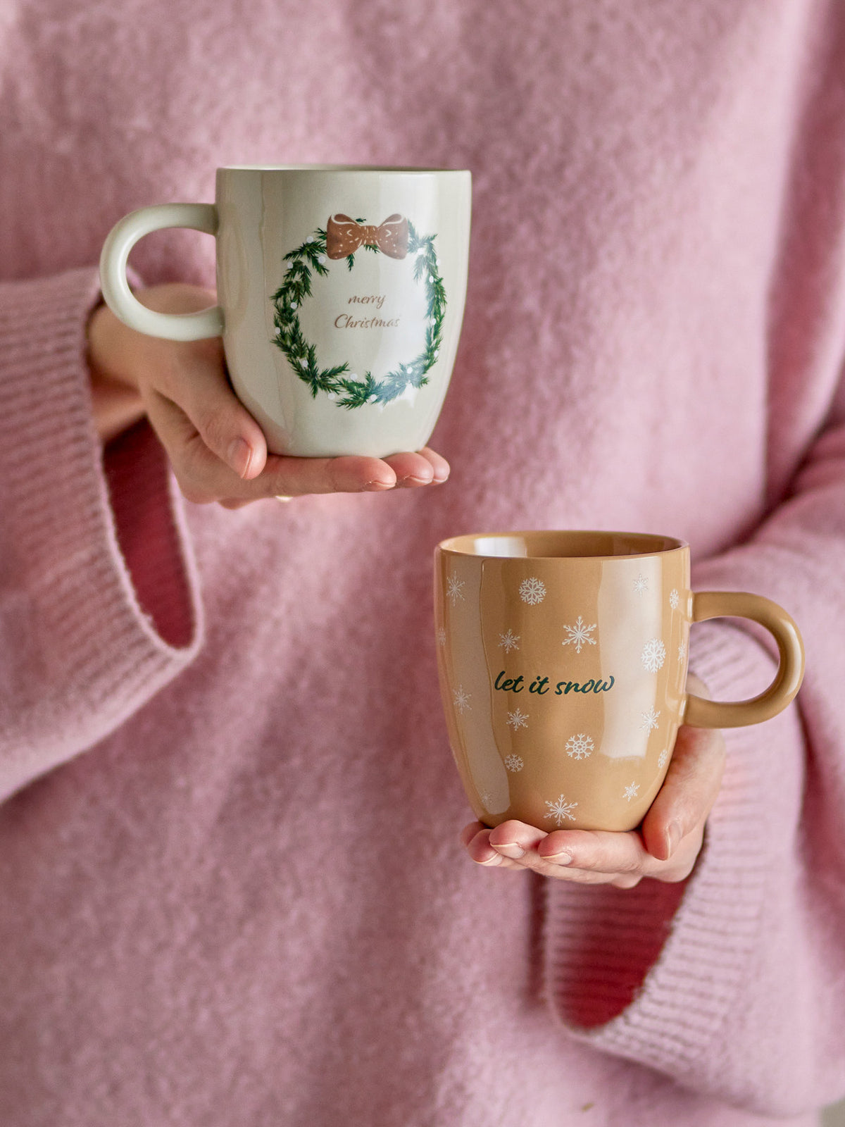 Zwei weisse Steingut-Becher der Serie Jolina von Bloomingville mit Abziehbild-Dekoration, einer mit Schneeflocken, einer mit Weihnachtskranz-Motiv
