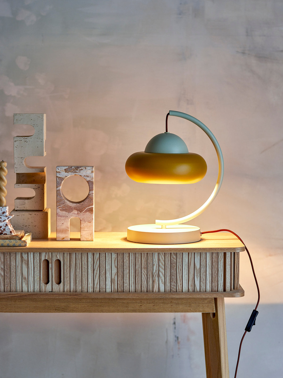 Weisse Bubble Tischlampe aus Eisen von Bloomingville mit geschwungenem Arm und rundem Lampenschirm, braunes Kabel sichtbar, skulpturale Form