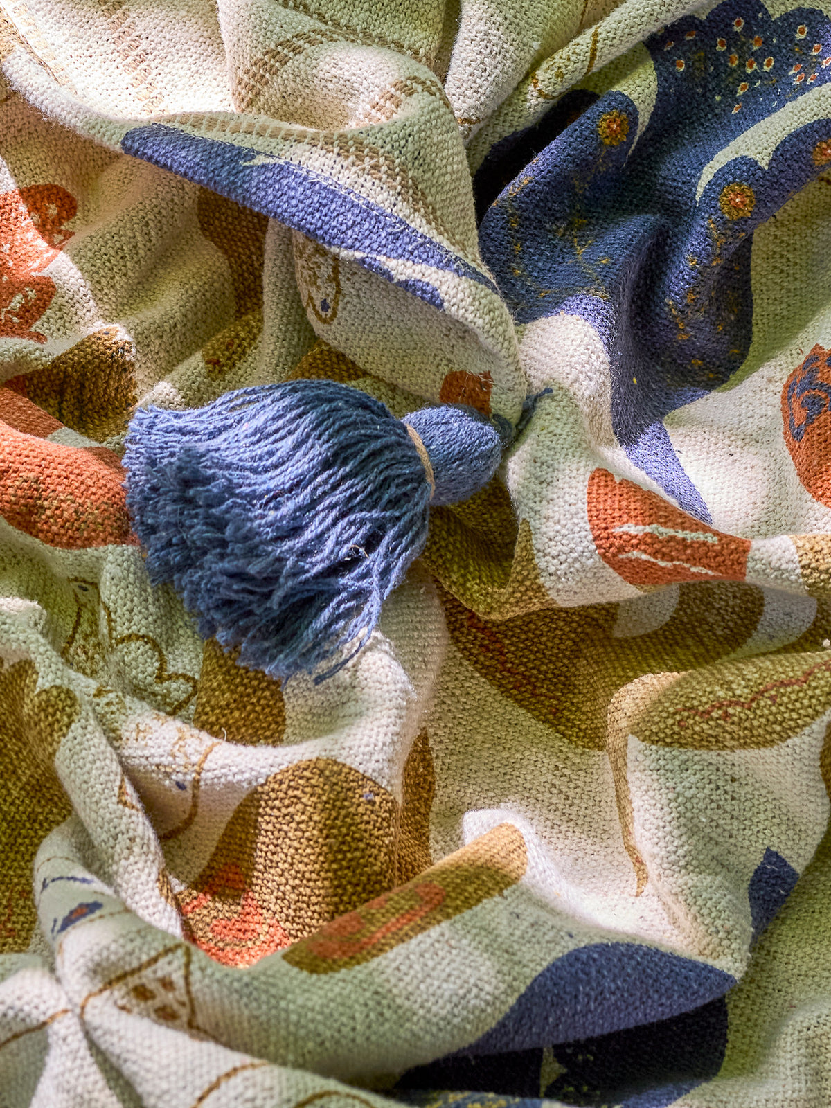 Wolldecke Anniversary von Bloomingville in Braun mit buntem botanischem Druckmuster, aus Baumwolle, Polyester und Viskose, mit blauen Quasten an den Ecken.