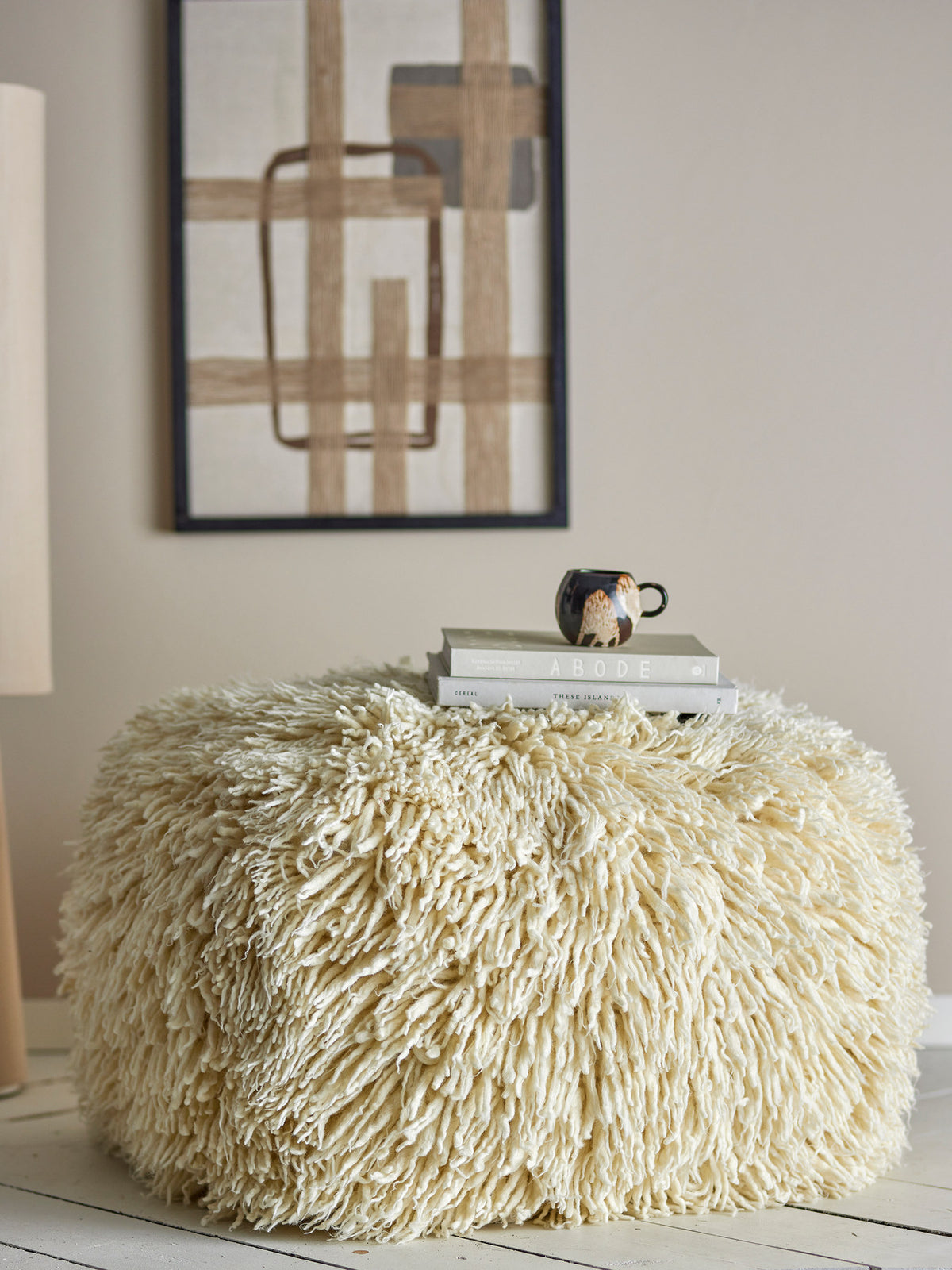 Weisser Lomba Pouf von Bloomingville aus Wolle und Baumwolle mit dichtem Fransenbesatz, runder Form und Beinen in Natur, strukturierte Oberfläche.