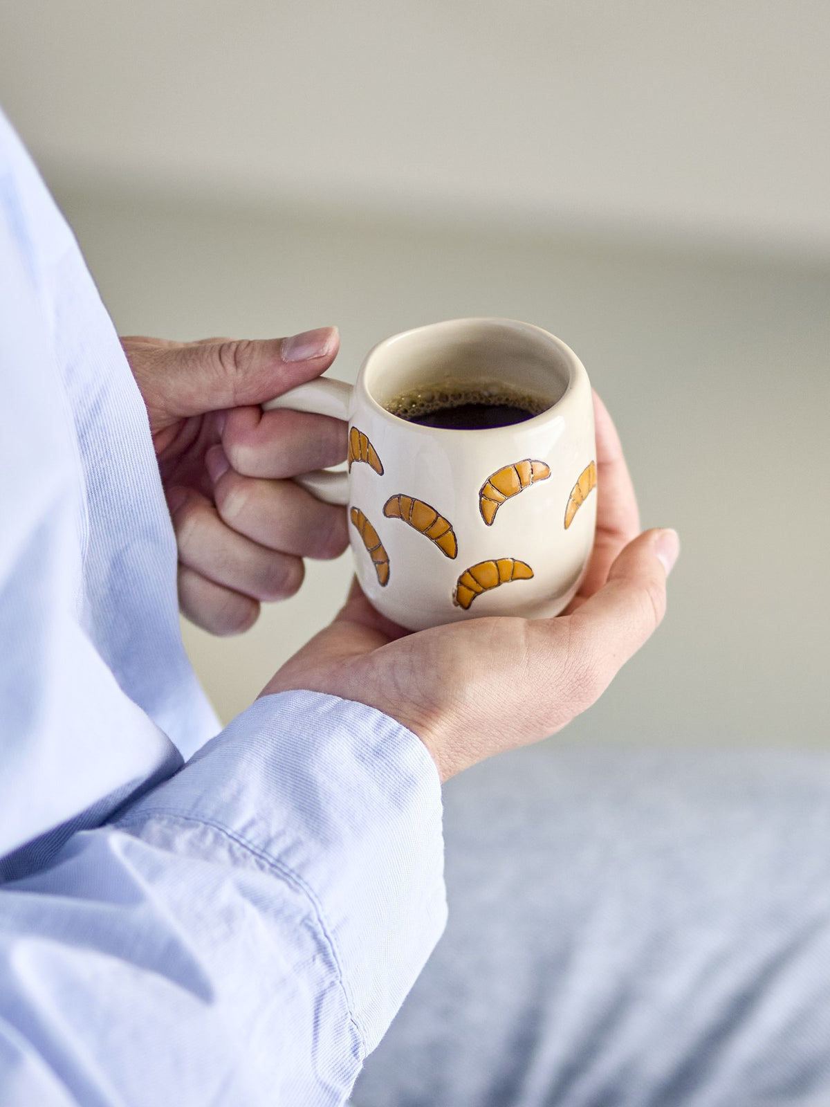 Millie Tasse von Bloomingville Mini aus Steingut, handbemalt mit Croissant-Motiven in Orange, Beige und Grün, kleine runde Form.