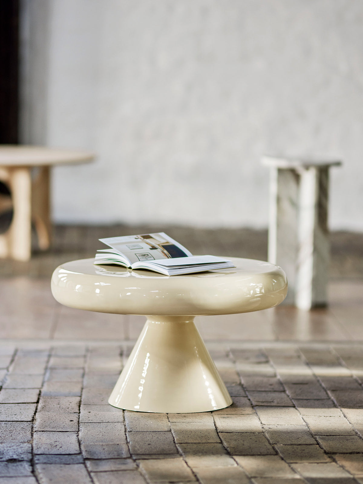 Ricko Couchtisch von Bloomingville in Beige, aus Eisen und MDF, mit runder Tischplatte auf konisch zulaufendem Säulenfuss und emaillierter Oberfläche.