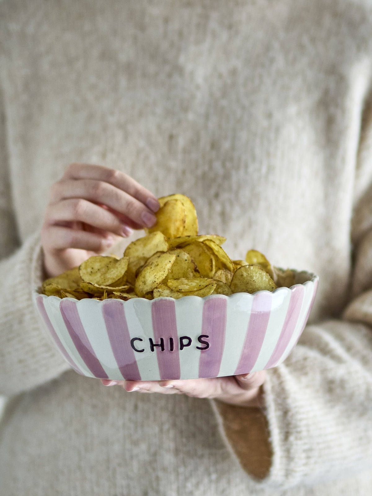 Rosafarbene Steingutschale mit gewelltem Rand, handbemalten vertikalen Streifen aussen und feinen Punkten innen, Schriftzug CANDY an der Seite.