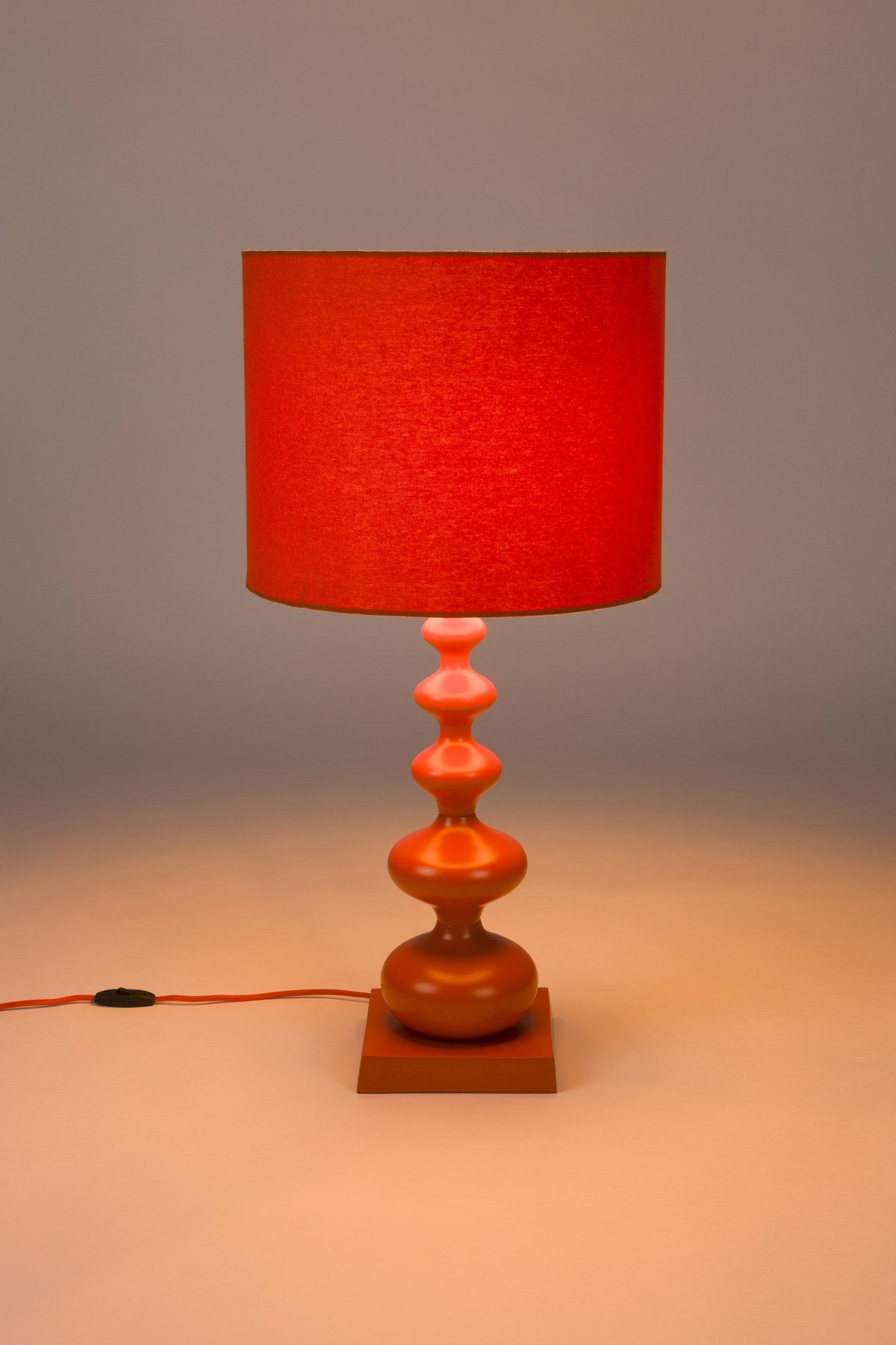 Stehlampe von Bold Monkey aus Eisen in leuchtendem Orange, geschwungene Form, mit E27-Fassung, Höhe 78 cm, für den Innenbereich.