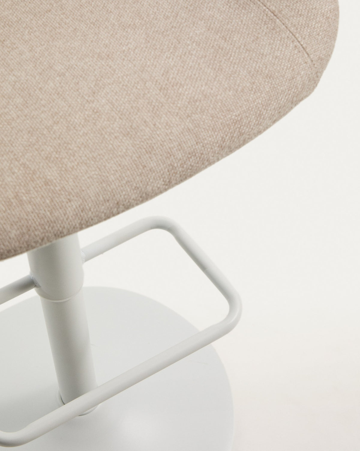 Runder Hocker mit beigem Chenillebezug, gepolstertem Sitz und mattweissem Stahlgestell mit rundem Fussring, freigestellt fotografiert.