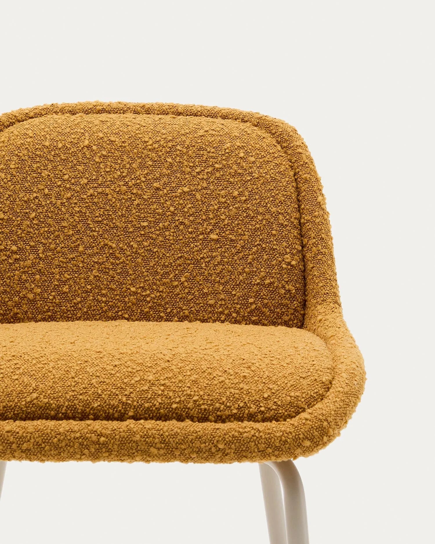 Eleganter Hocker in Senfgelb mit Bouclé-Bezug und stabilen Stahlbeinen, ideal für stilvolle und nachhaltige Einrichtung.