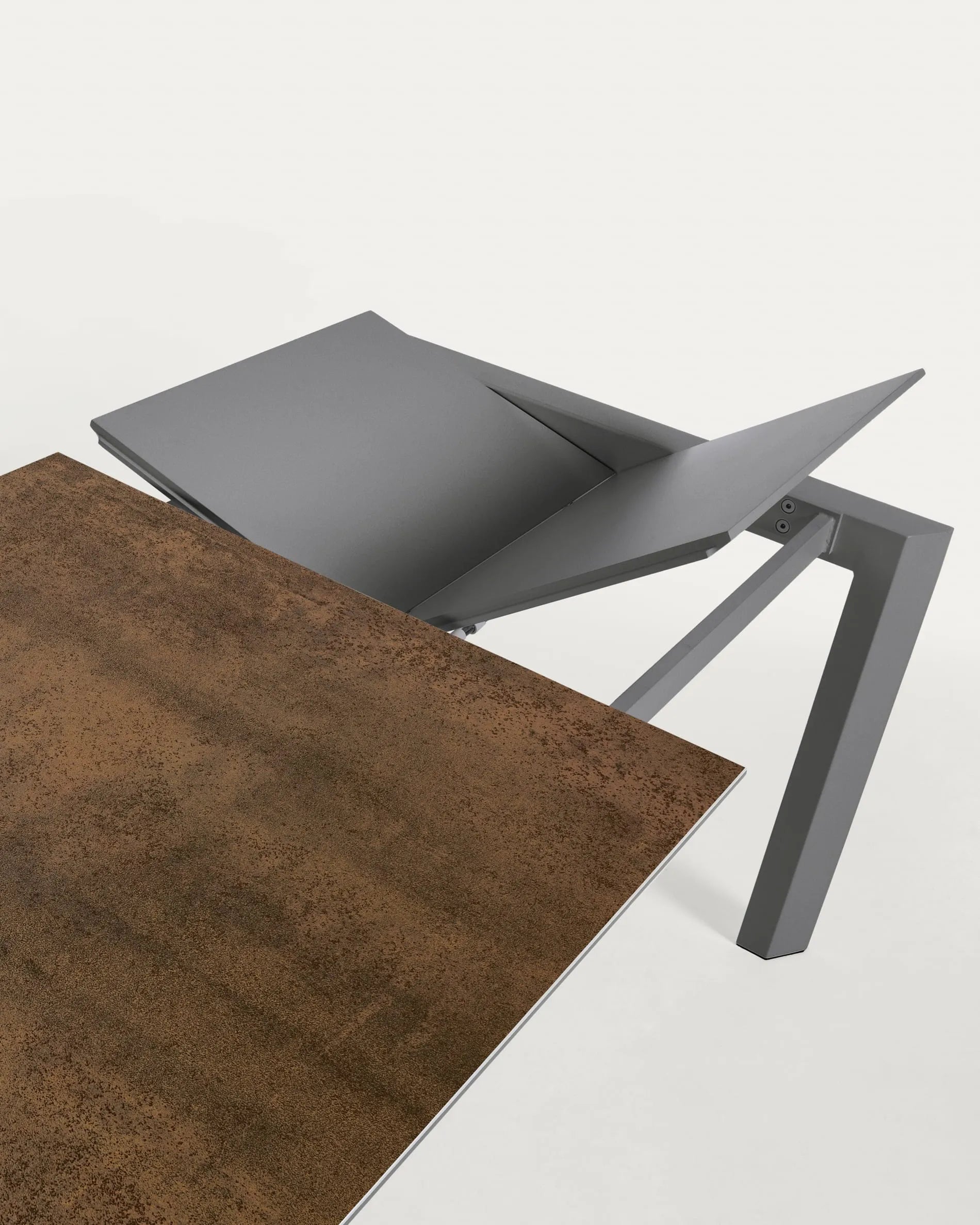 Moderner Ausziehtisch mit robuster Feinsteinzeugplatte im Iron Corten Finish und eleganten, dunkelgrauen Metallbeinen.