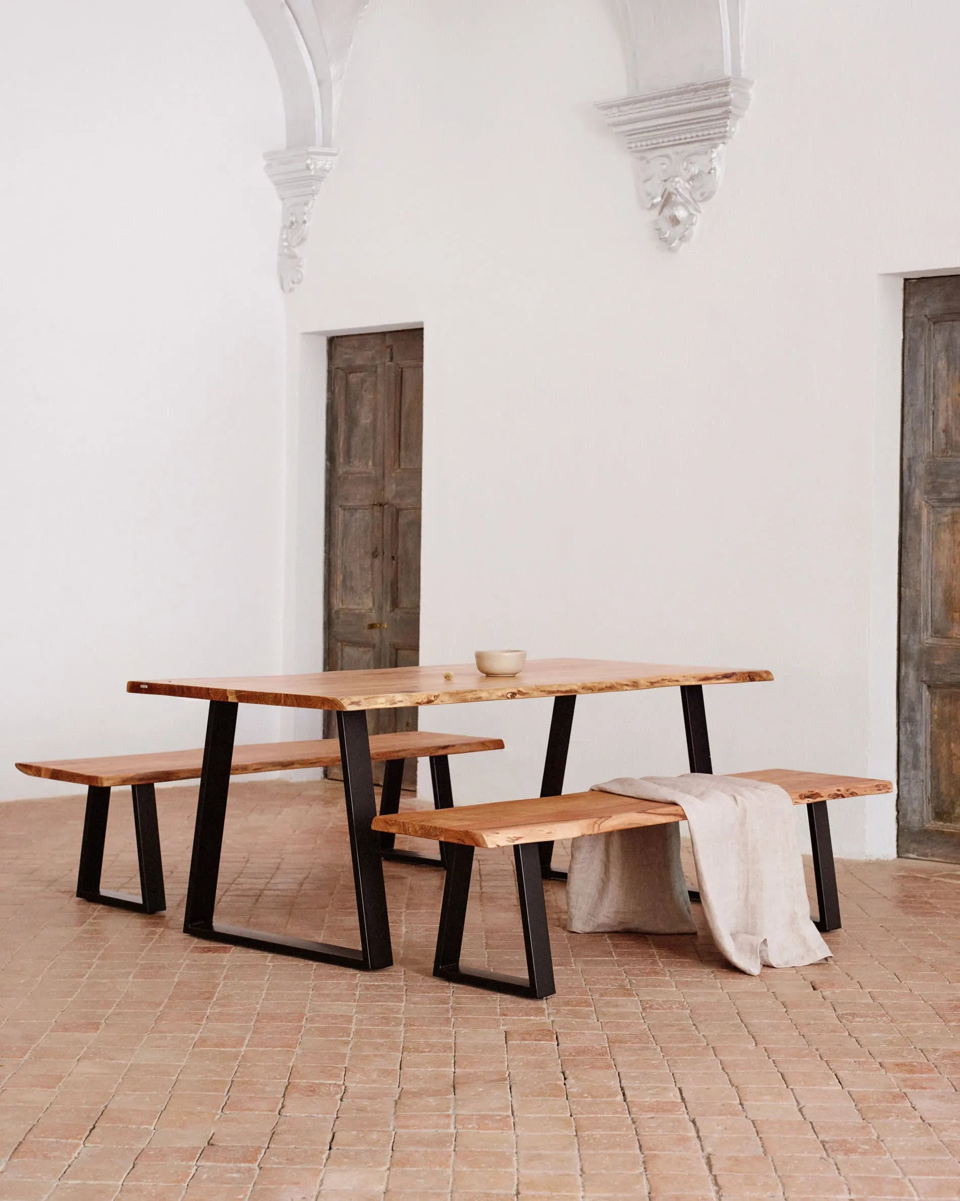 Eleganter Tisch aus Akazienholz mit schwarzen Stahlbeinen, ideal für stilvolle Zusammenkünfte und langlebige Qualität.