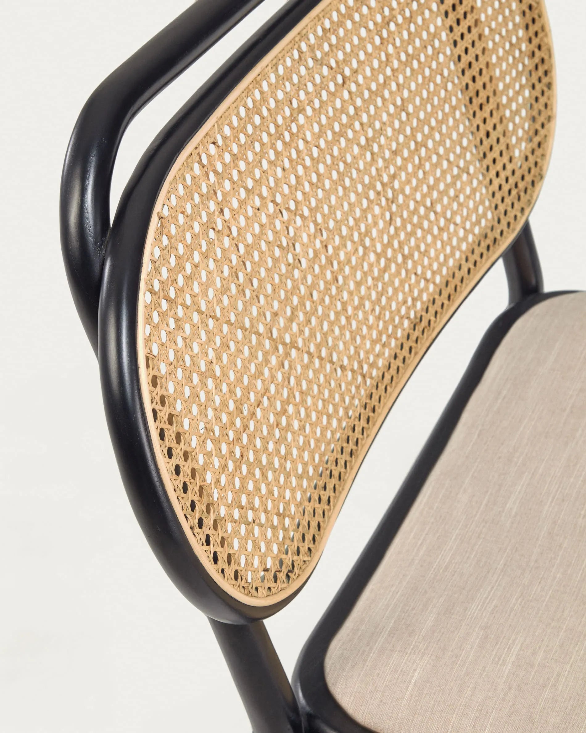 Eleganter Sessel aus massiver Ulme mit schwarzem Finish, Rattanrücken und wasserabweisender Polsterung für stilvollen Komfort.