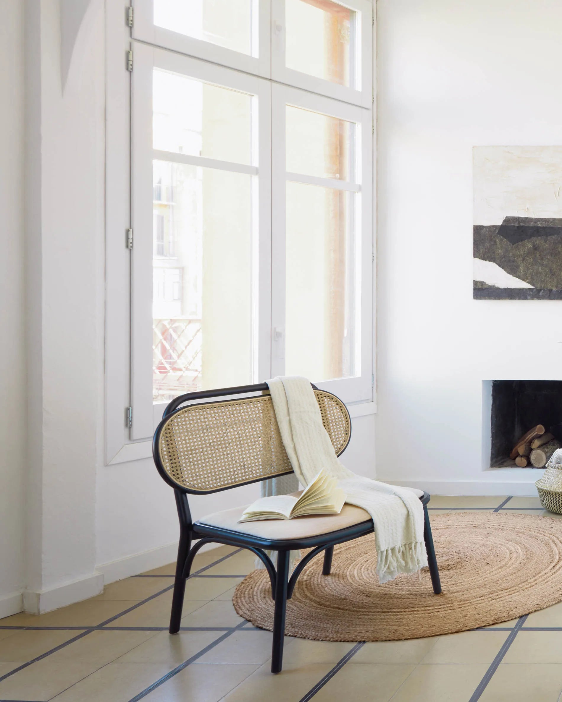 Eleganter Sessel aus massiver Ulme mit schwarzem Finish, Rattanrücken und wasserabweisender Polsterung für stilvollen Komfort.