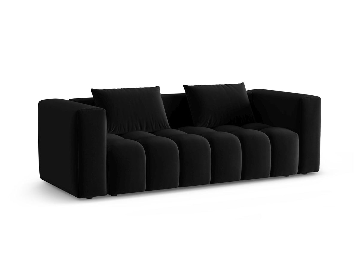 Sandfarbenes Samt-Bettsofa Verona mit drei Sitzplätzen, ausklappbarer Liegefläche, Bettkasten und schwarzen Kunststoffbeinen im Wohnraum.