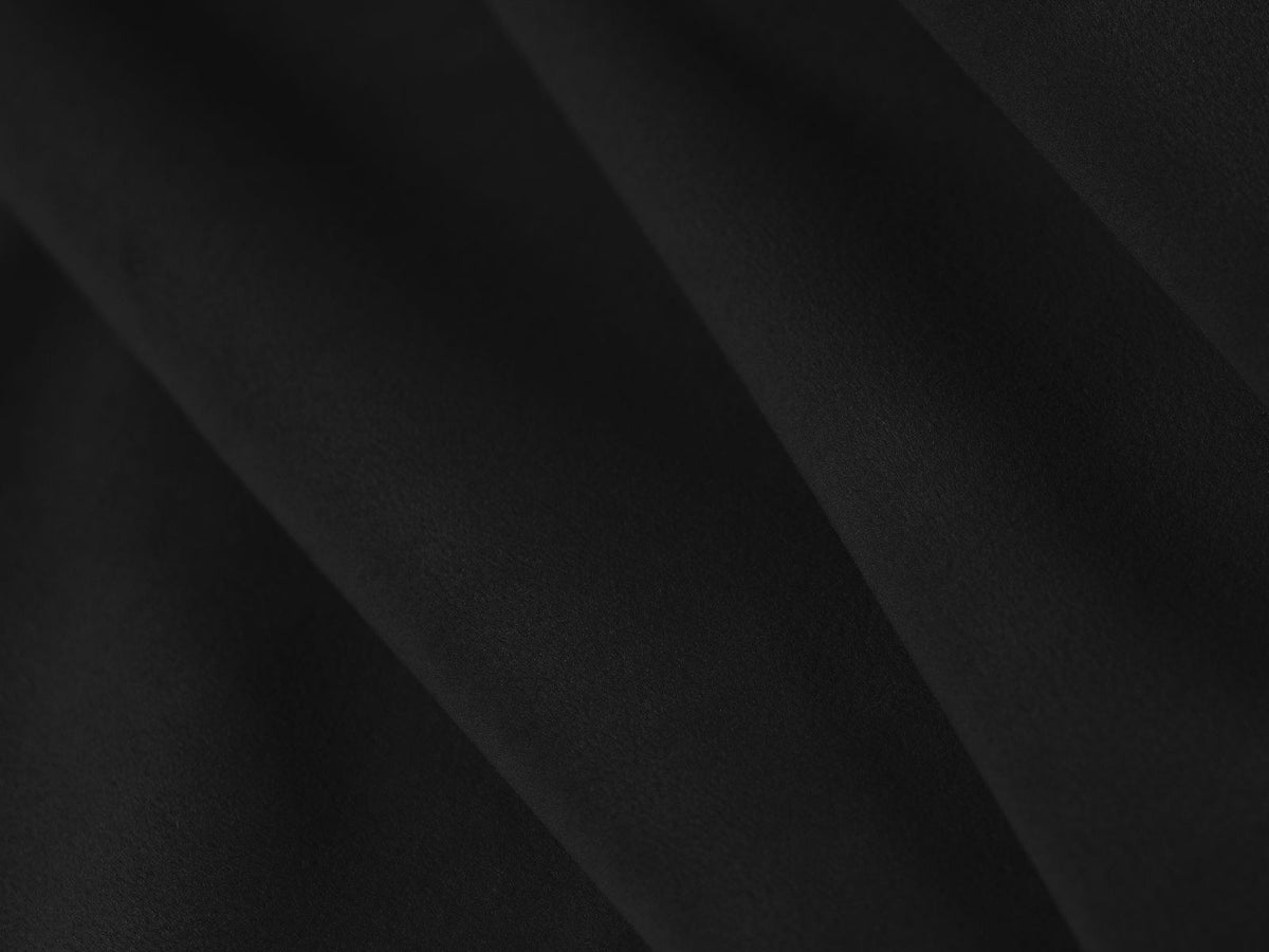 Sandfarbenes Samt-Bettsofa Verona mit drei Sitzplätzen, ausklappbarer Liegefläche, Bettkasten und schwarzen Kunststoffbeinen im Wohnraum.