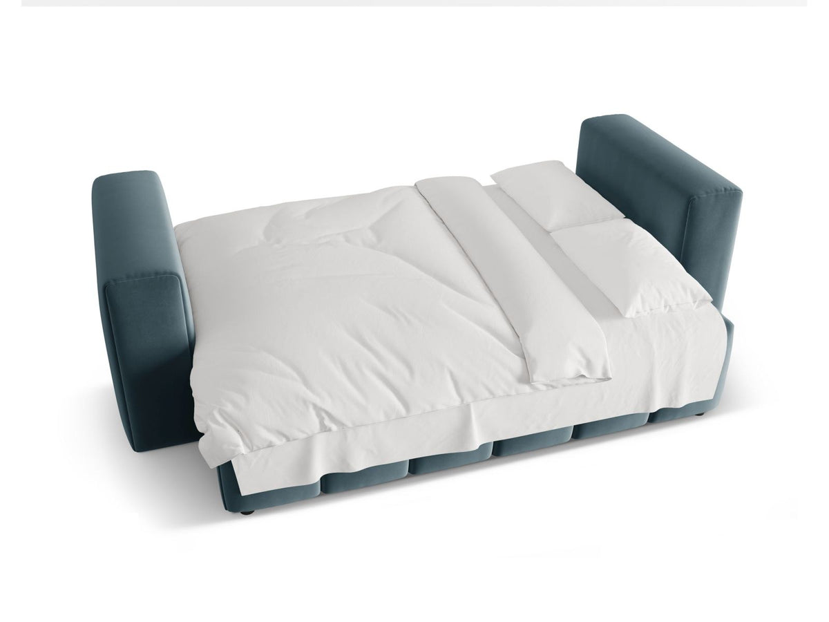 Sandfarbenes Samt-Bettsofa Verona mit drei Sitzplätzen, ausklappbarer Liegefläche, Bettkasten und schwarzen Kunststoffbeinen im Wohnraum.