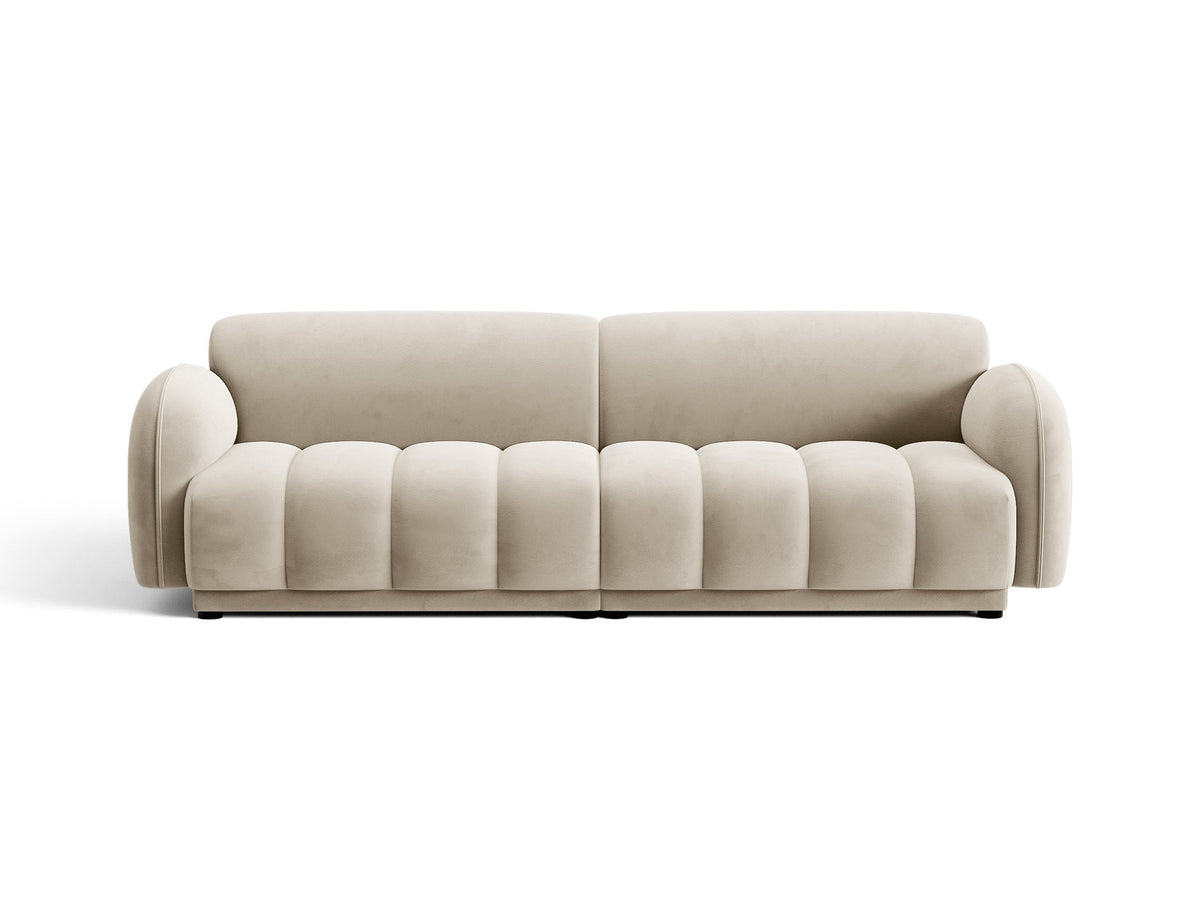 Vierersofa Bilbao mit hellbeigem Samtbezug, schwarzen Kunststoffbeinen und klarer, gerader Linienführung, fotografiert freistehend im Raum.