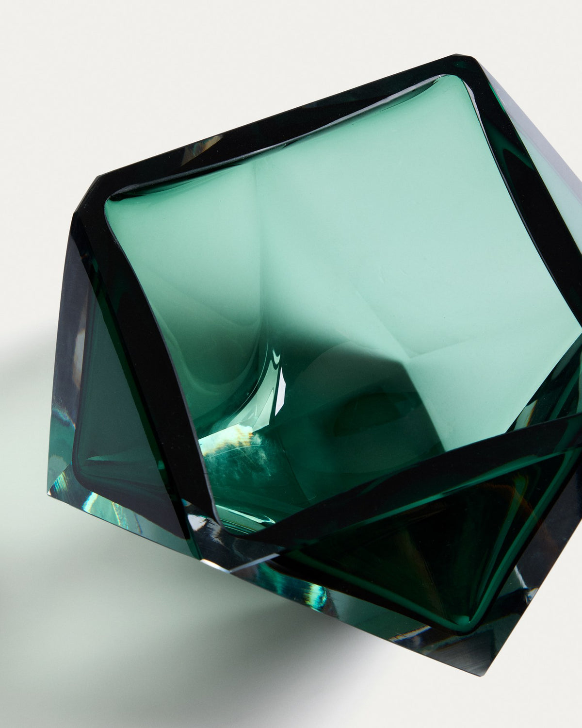 Facettierter Tafelaufsatz aus smaragdgrünem Glas mit runder Öffnung, mundgeblasen gefertigt, auf weissem Hintergrund fotografiert.