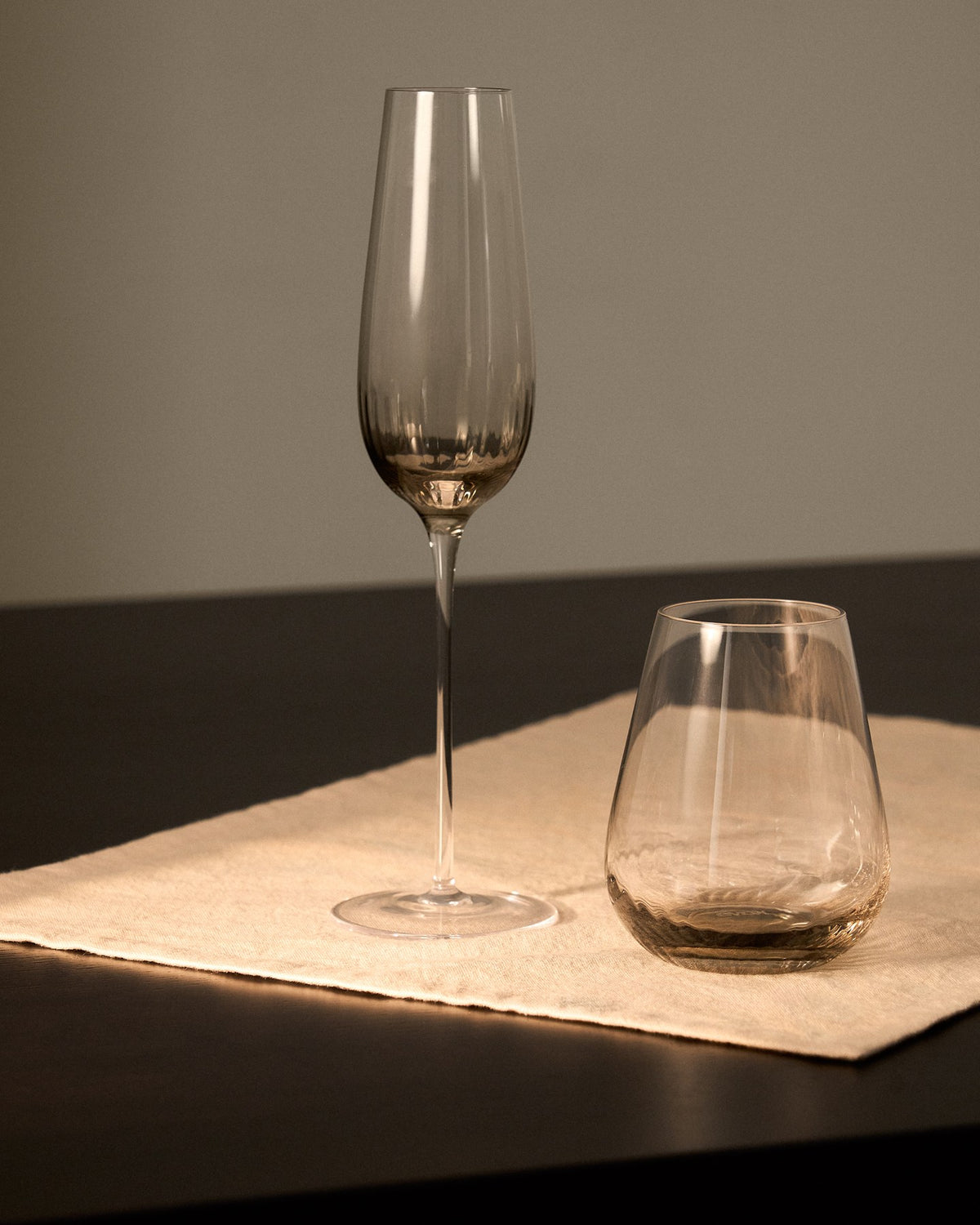 Hellgraues Trinkglas aus 100% Glas mit abgerundeter Basis und grauem Boden, klare Oberfläche, kompakte Form für Getränke.
