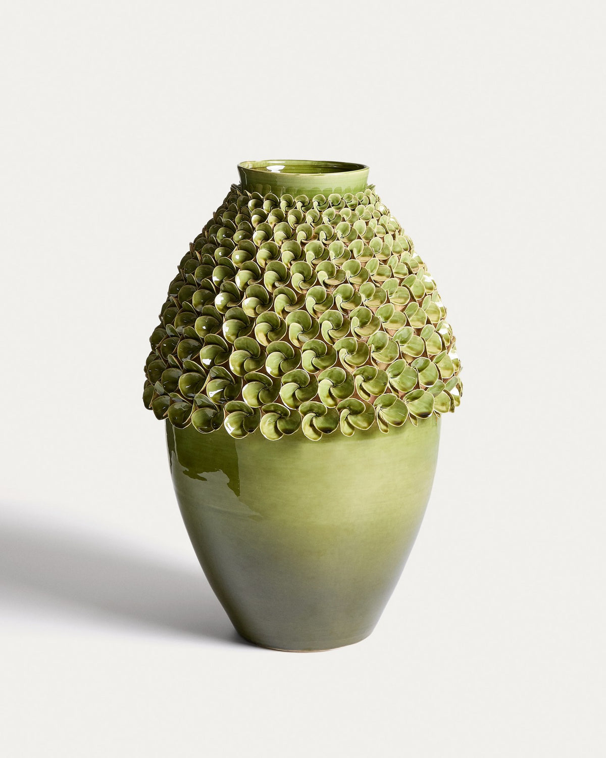 Hellgrüne Keramikvase Ederia von Kave Home mit floralen, handgeformten Blütenelementen, glasierter Oberfläche und rundlicher Form.