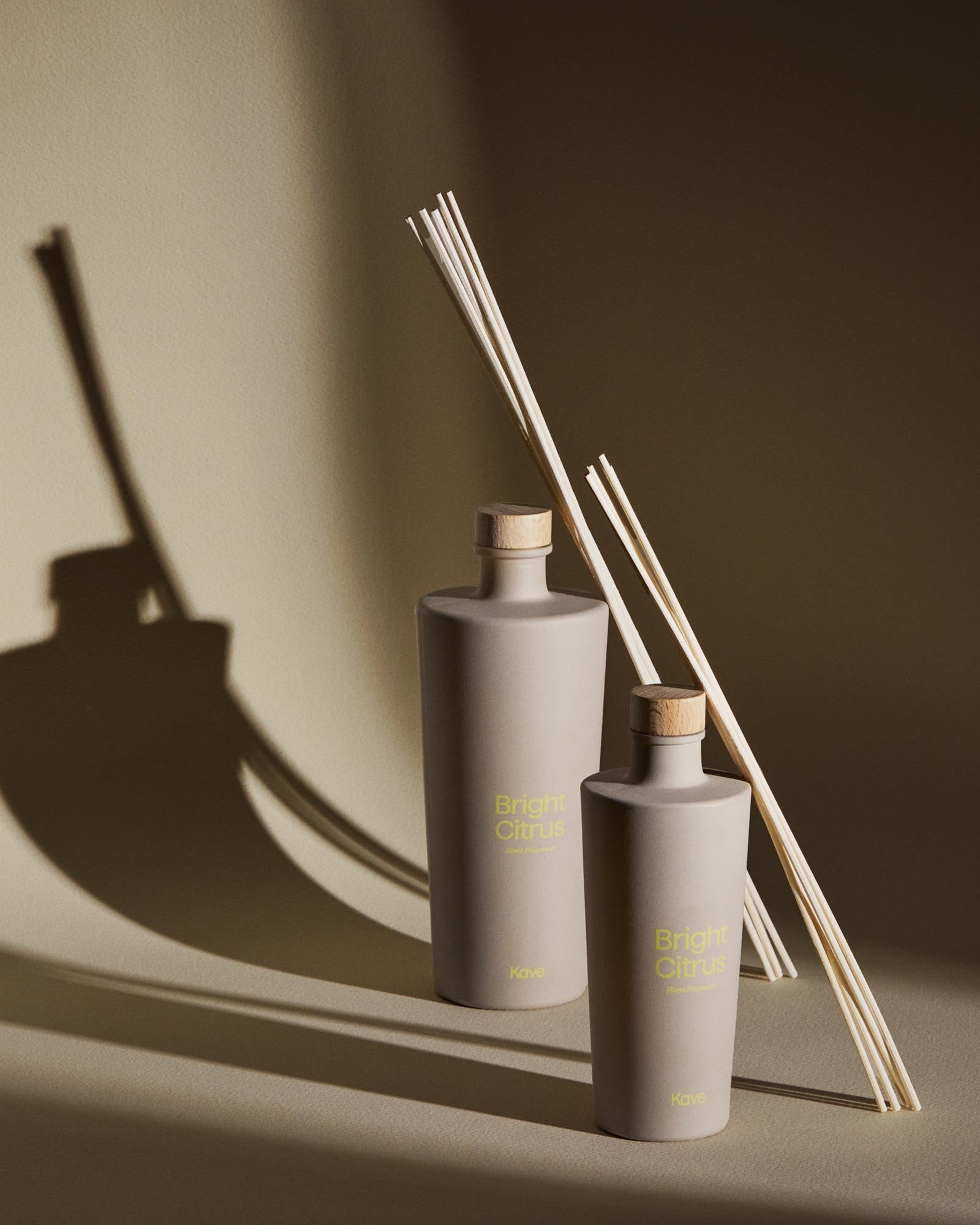 Stimmungsvolles Bild des Kave Home Citronella-Lufterfrischers Bright Citrus mit Stäbchen, 500 ml, in eleganter beige Verpackung.