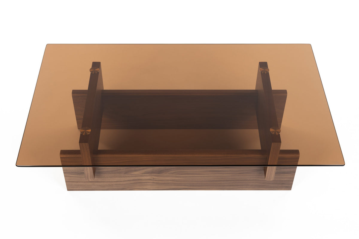 Couchtisch Lucifer Walnut von Dutchbone mit braunem Holzgestell aus zwei quer angeordneten Platten und rechteckiger Glasplatte.